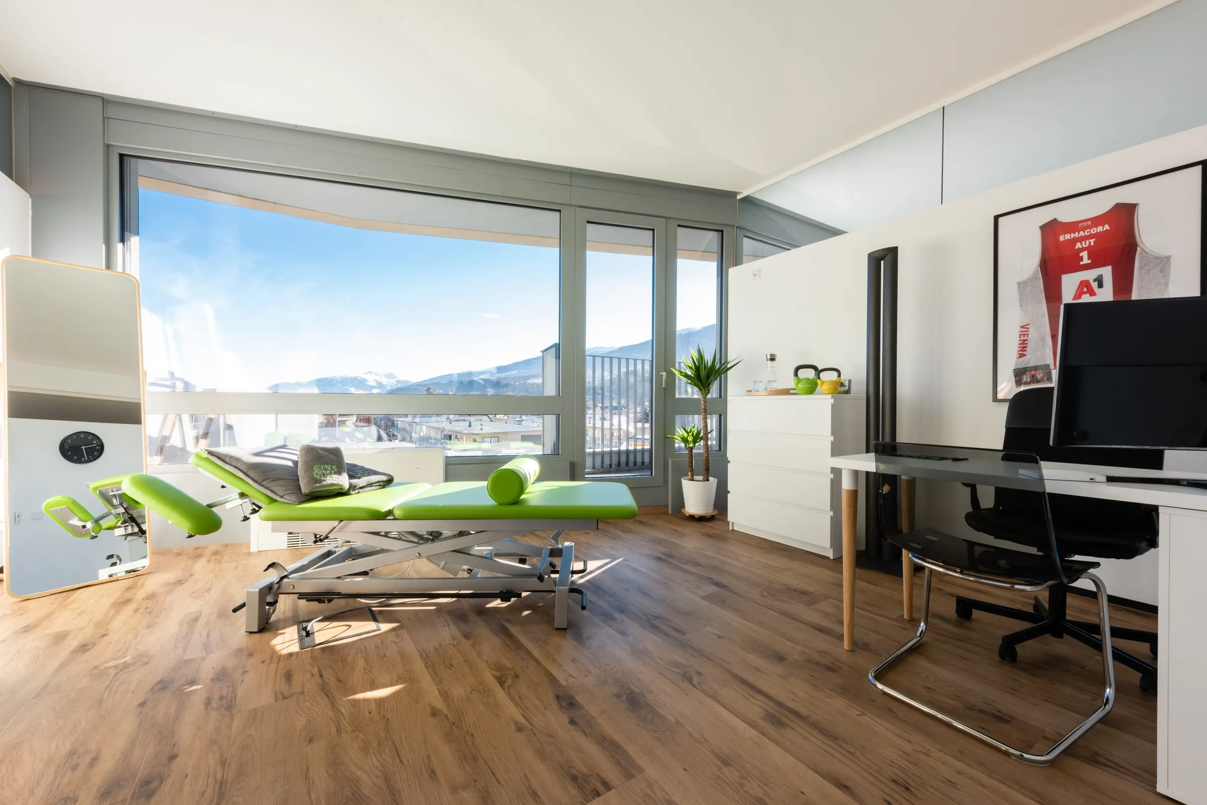 Treatment room at Physio 1.0 with a treatment table and a view of the snow-covered Nordkette mountains