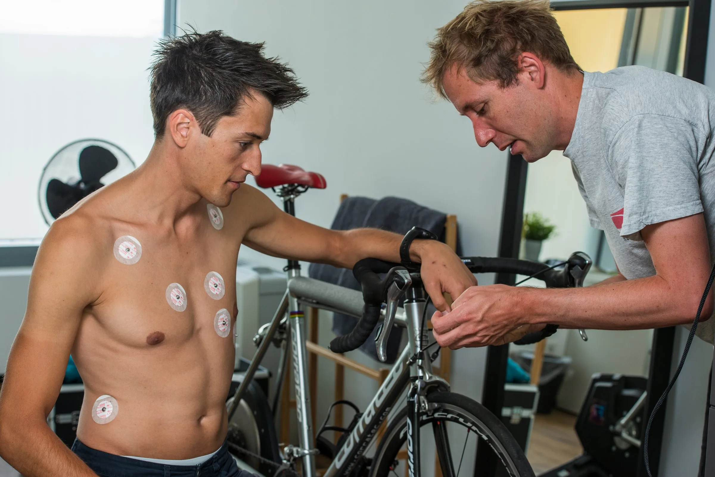 Athlete with ECG electrodes being prepared for performance testing on the bike