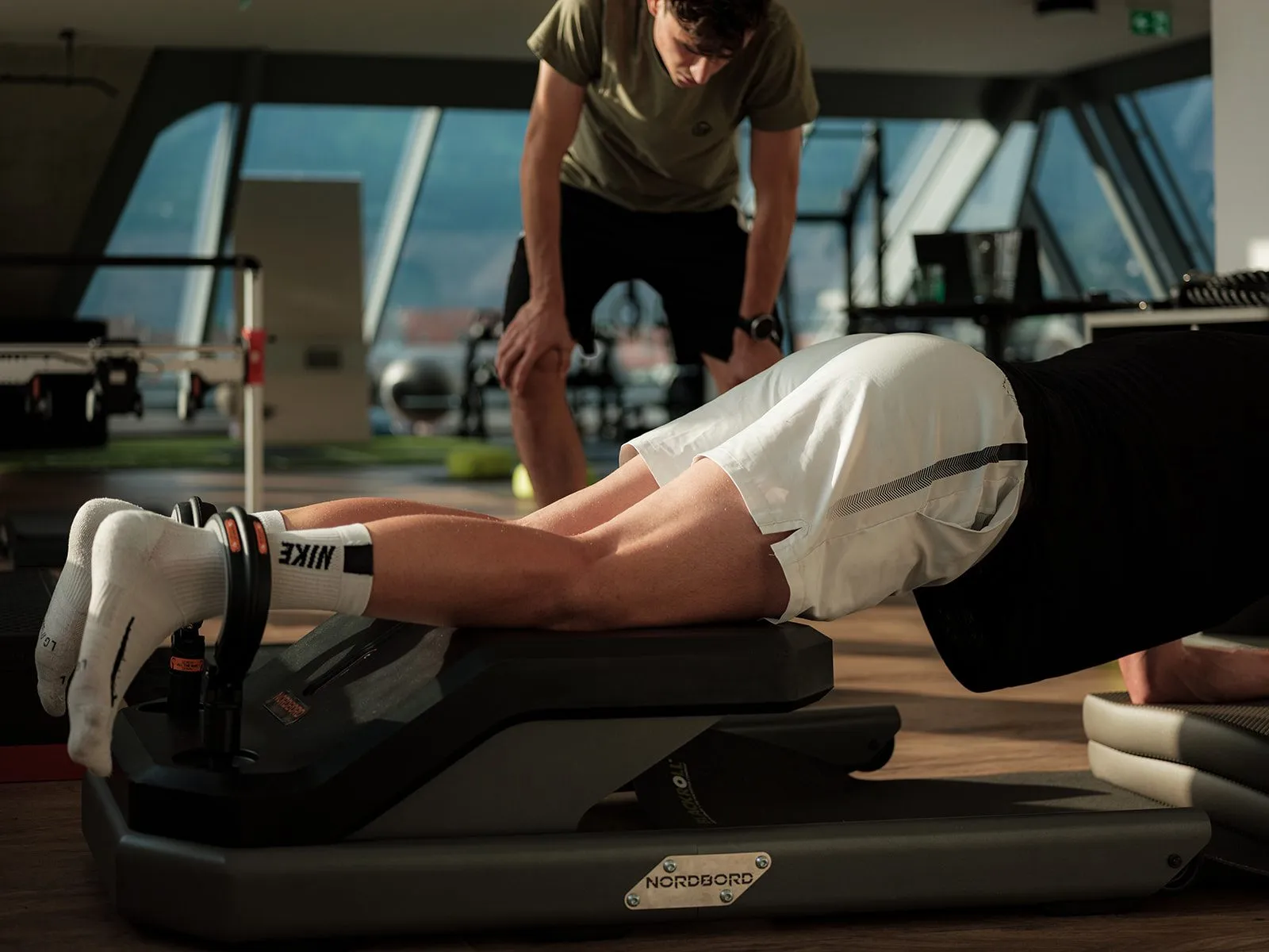 Athlete during Nordic hamstring strength testing, with a sports scientist spotting
