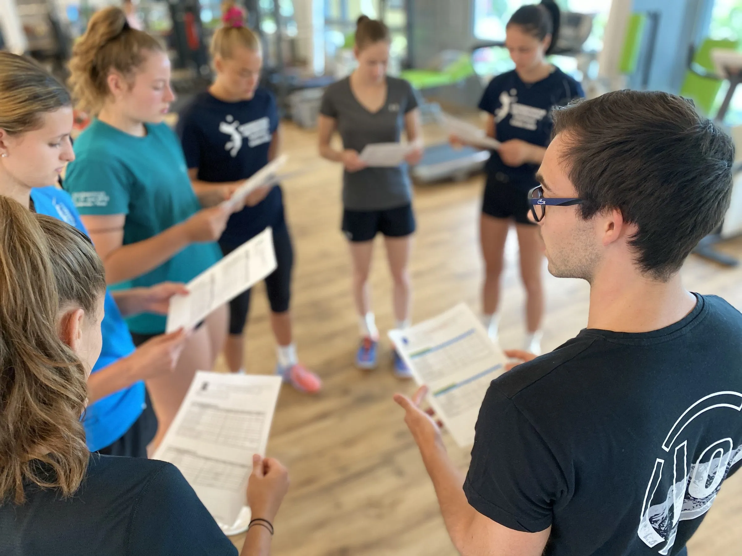Athletes with handouts at a workshop with a trainer